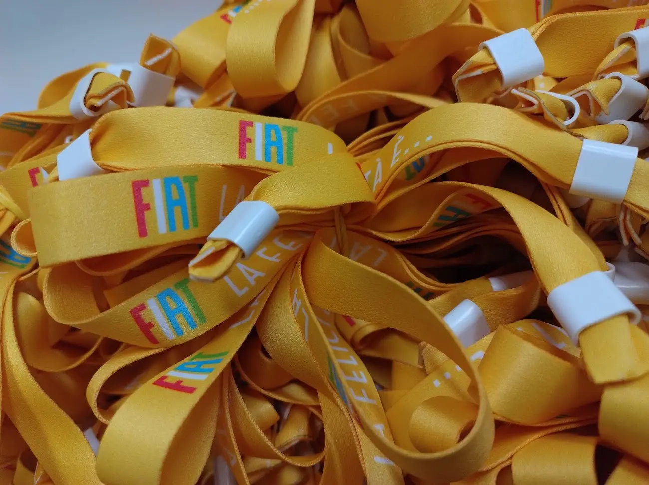 Bracciali gialli personalizzati con grafica full colour, realizzati per un evento di un brand automotive.